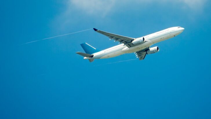 Avión volando en el cielo azul con nubes esparcidas