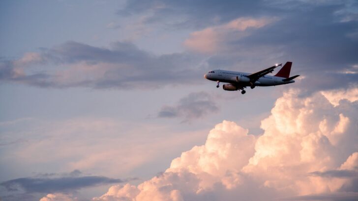 Avión volando entre nubes al atardecer en un cielo despejado