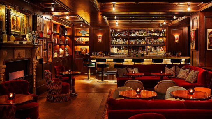 Interior de un bar de hotel elegante con sofás rojos y barra iluminada