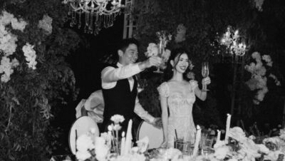 Pareja en boda en Bali brindando rodeados de flores y candelabros