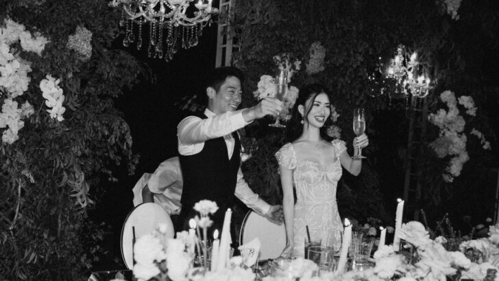 Pareja en boda en Bali brindando rodeados de flores y candelabros