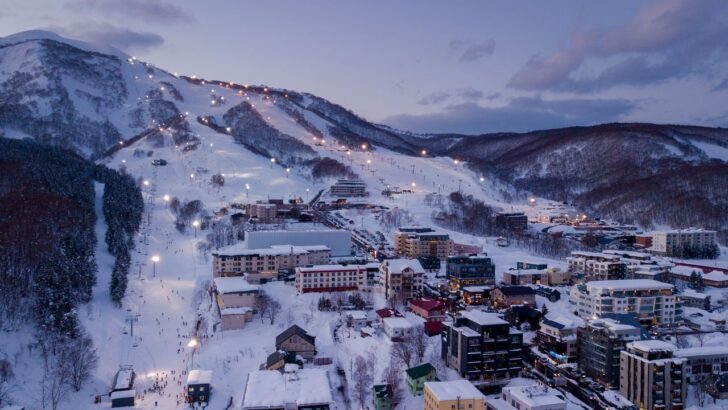 Vista panorámica de un centro de esquí en Japón al atardecer con luces encendidas