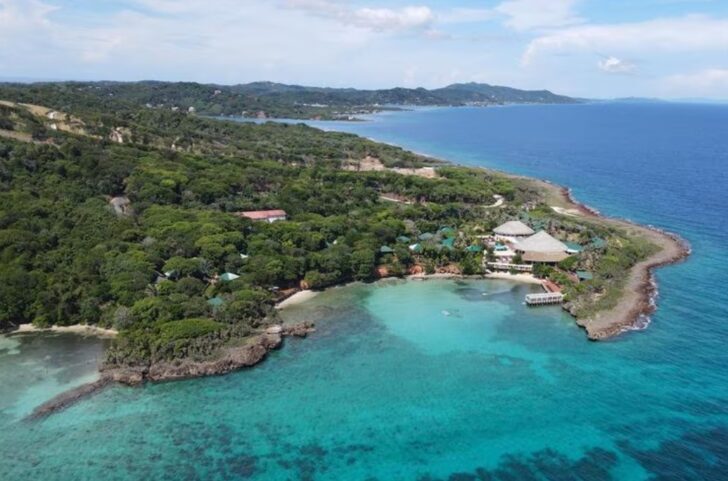 Vista aérea de un hotel rodeado de vegetación y mar en Roatán, Honduras