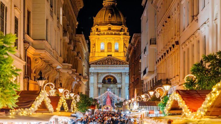 Mercado navideño europeo con luces y catedral iluminada al fondo
