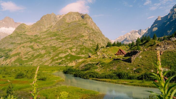 Vista de montañas verdes con una cabaña y un río en el Mont Blanc