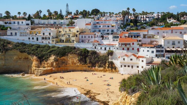 Vista de una playa con casas blancas en Algarve, Portugal, bajo un cielo despejado