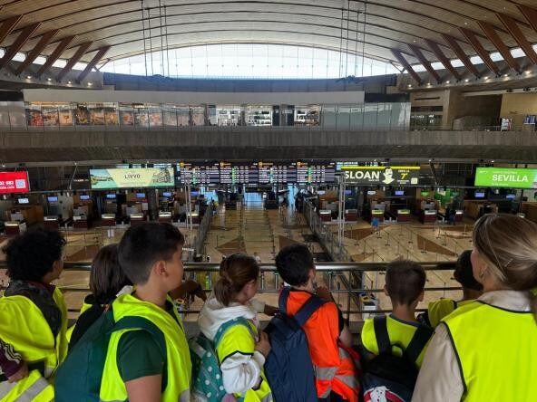 Grupo de estudiantes observando el área de embarque en un aeropuerto