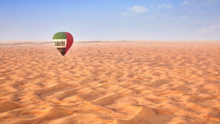 Globo aerostático sobrevolando el desierto de Dubái bajo un cielo despejado