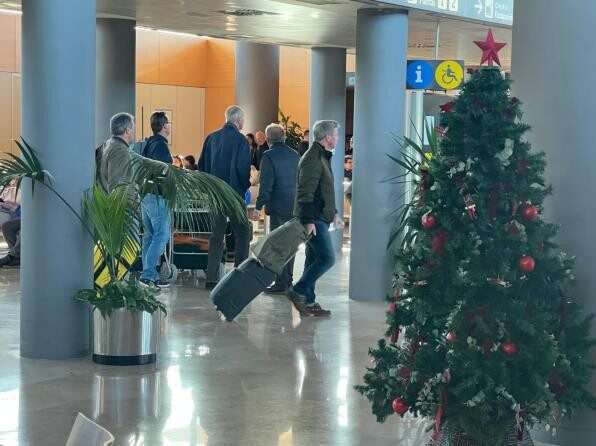 Viajeros en un aeropuerto decorado con árbol de Navidad