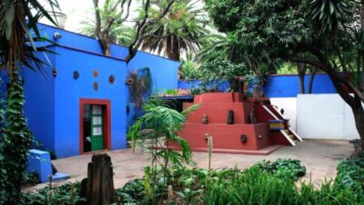 Vista del jardín exterior del Museo Frida Kahlo con paredes azules y vegetación