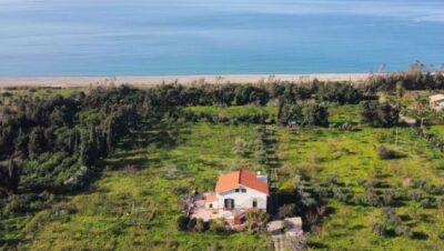 Casa de campo en Sicilia con techo rojo, rodeada de vegetación y vista al mar