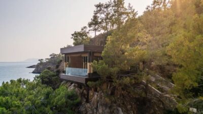 Casa moderna de madera en un acantilado con vista al mar y rodeada de árboles