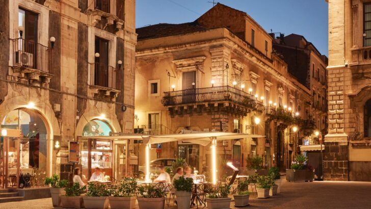 Personas cenando al aire libre en una calle italiana iluminada por la noche