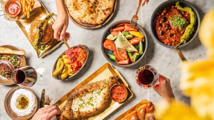 Mesa con variedad de platos de comida judía y manos sirviendo