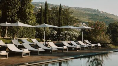 Piscina con tumbonas y sombrillas frente a montañas verdes