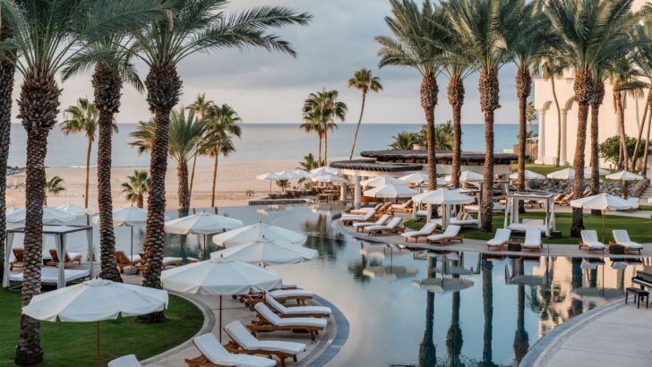 Vista de un lujoso resort en Los Cabos con piscina y palmeras frente al mar