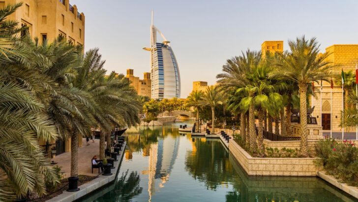 Vista del Burj Al Arab desde un canal rodeado de palmeras en Dubái
