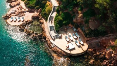 Vista aérea de un resort costero con terrazas y tumbonas junto al mar